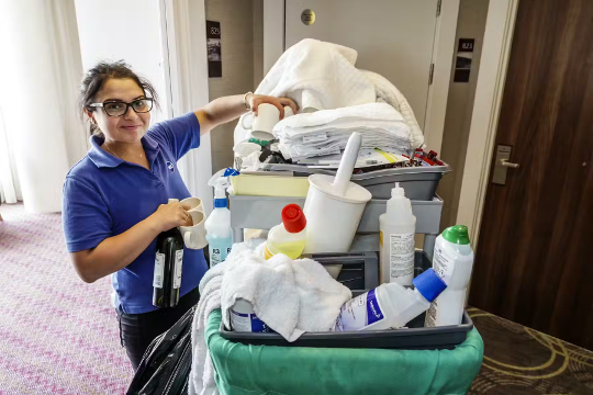 hotel housekeeper with a cart full of cleaning chemicals